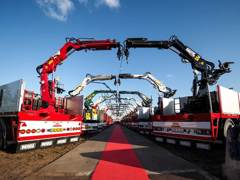 Rode loper tussen vrachtwagens met laadkranen tijdens een open dag