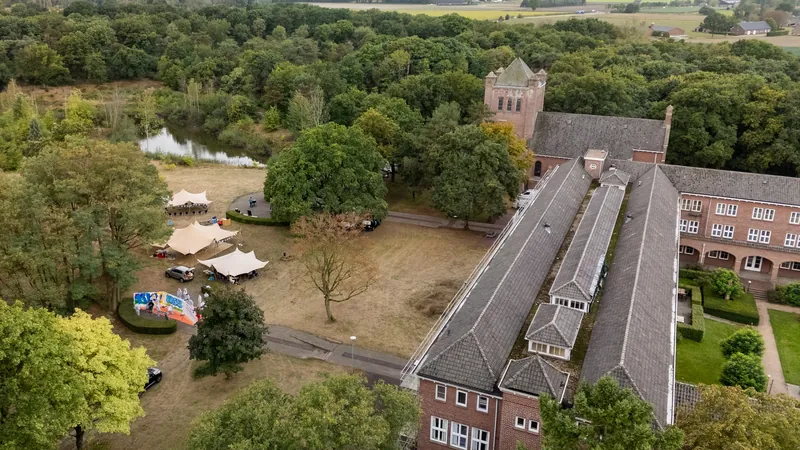 Dronefoto van een bedrijfsfeest op een landgoed met feesttenten naast een groot gebouw