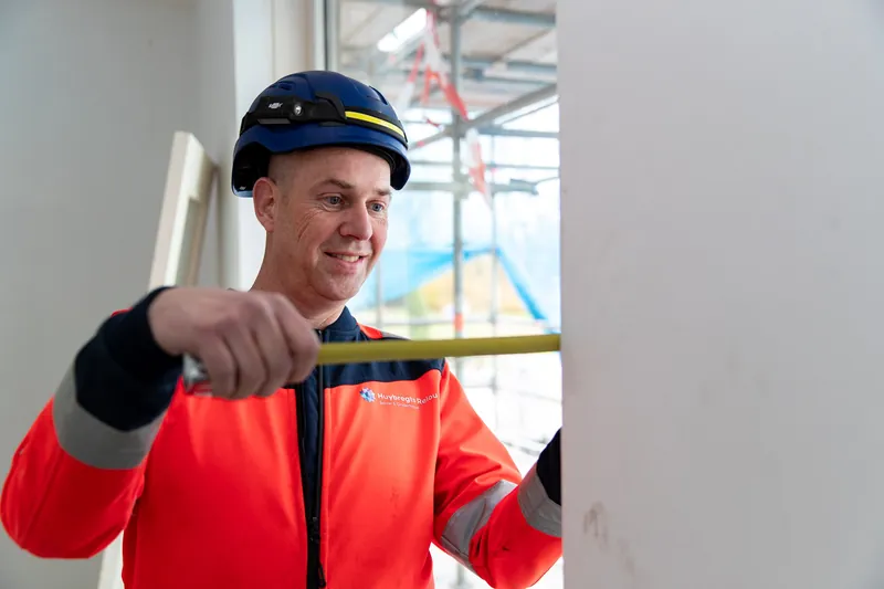 Bedrijfsreportage: vakman meet iets op met een rolmaat tijdens het werk
