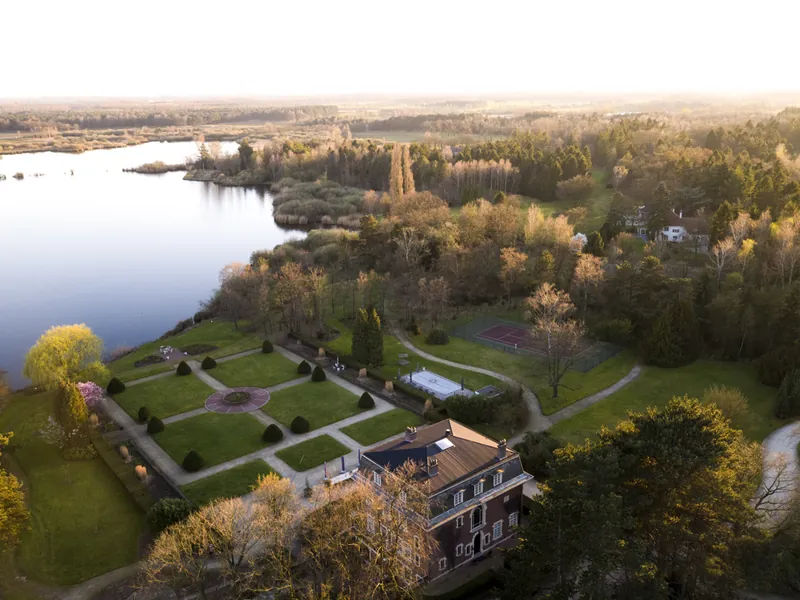 Dronefoto van een landgoed met tuinen aan het water