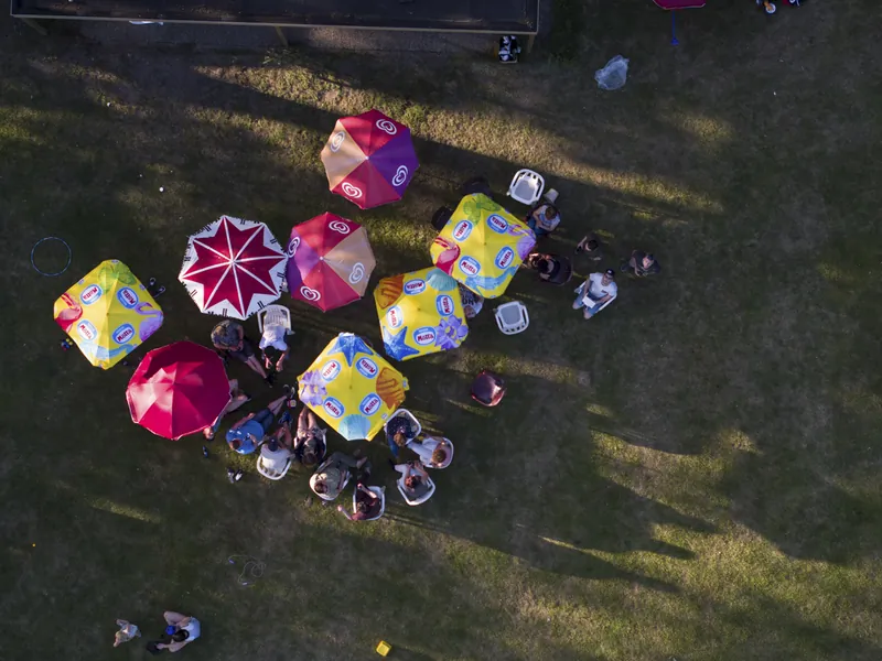 Dronefoto van kleurrijke parasols met mensen op een grasveld
