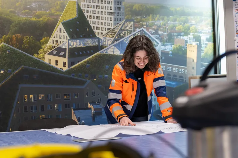 Zakelijk portret van een bouwprofessional die een tekening bestudeert met uitzicht over de stad