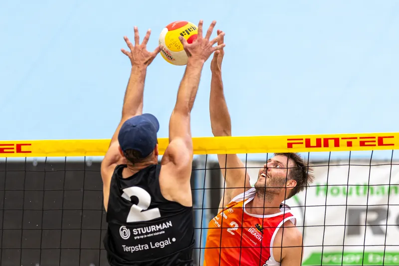 Beachvolleybalspeler springt hoog voor een smash bij het net