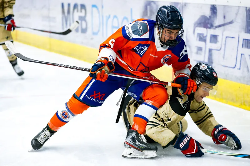 IJshockeyspelers in een duel op het ijs, een speler glijdt op de grond