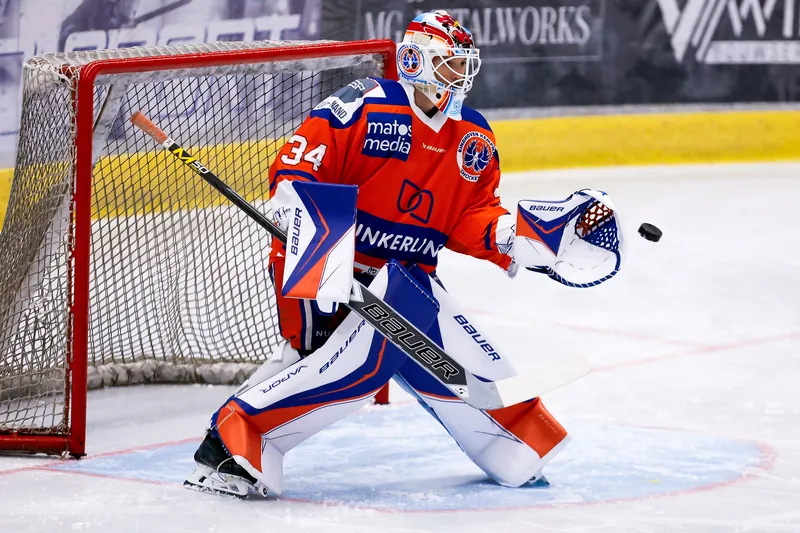 IJshockeykeeper vangt de puck bij het doel tijdens een competitiewedstrijd