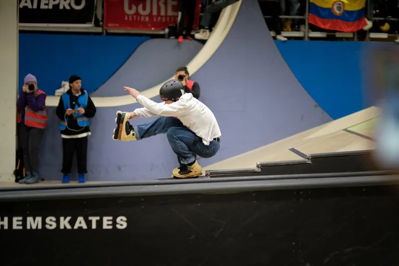 Inlineskater maakt een sprong tijdens een wedstrijd in een skatehal
