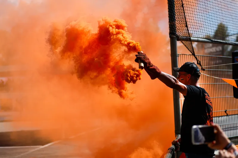 Toeschouwer met oranje rookfakkel tijdens het EK motoball in Budel