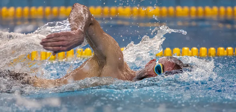 Zwemmer tijdens de borstcrawl, vastgelegd op het moment dat de arm door het water gaat