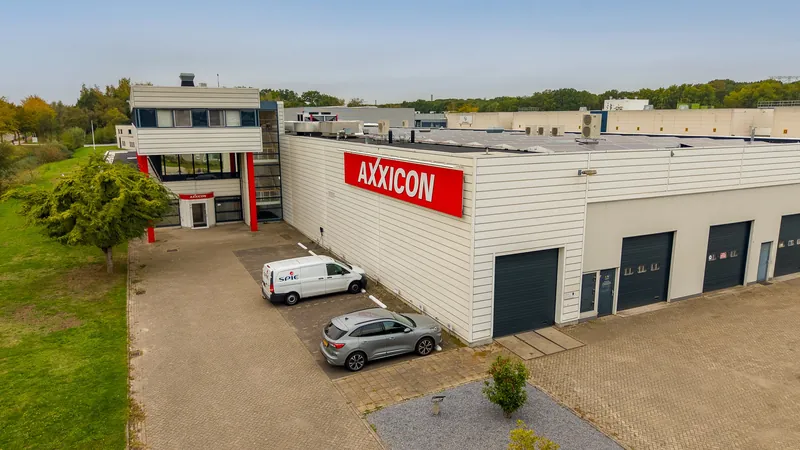 Dronefoto van een bedrijfspand met opvallend logo op de gevel en een groene omgeving