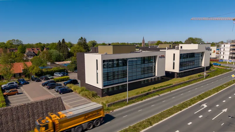 Dronefoto van een kantoorgebouw langs een provinciale weg met parkeerplaats