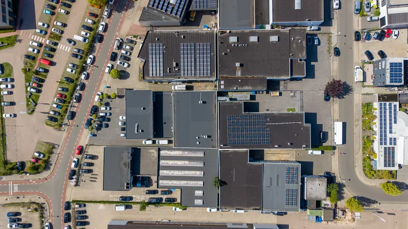 Dronefoto recht van boven op bedrijfsdaken met zonnepanelen en parkeerplaatsen