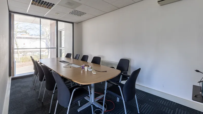 Interieur van een vergaderruimte met ovale tafel en veel daglicht